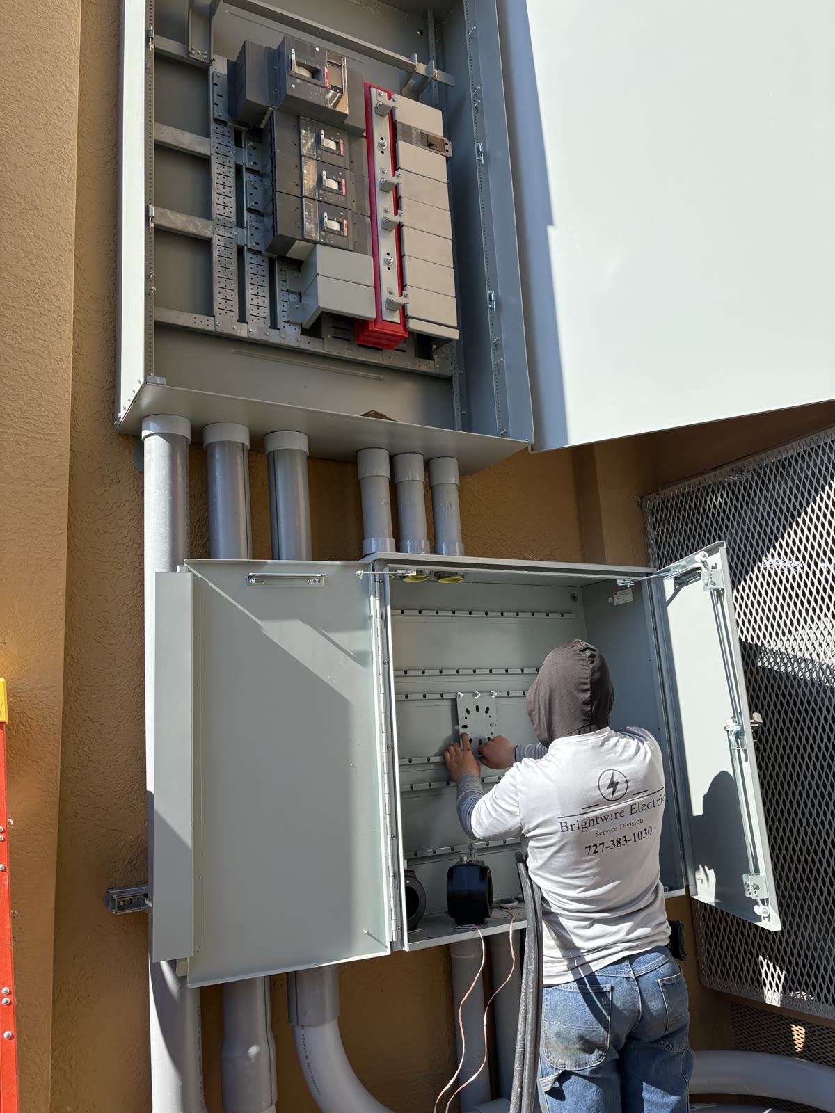 Brightwire electrician working in a waterfront electrical enclosure near the water