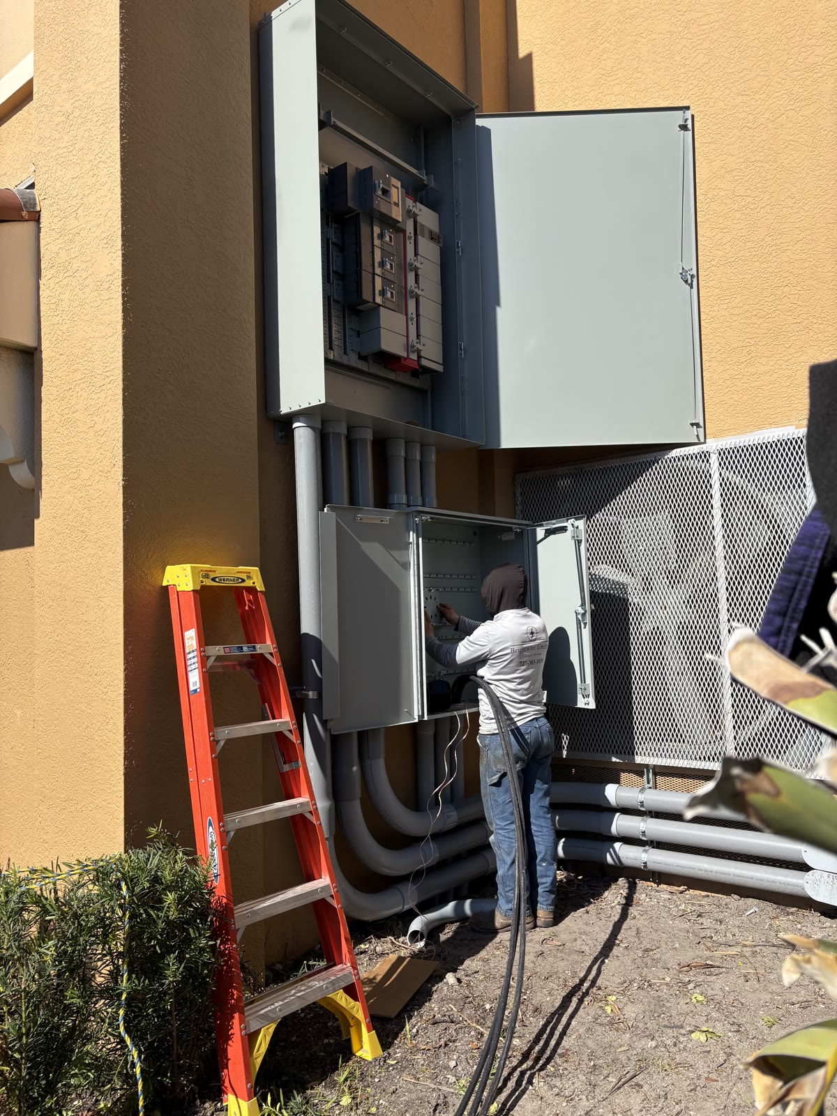 Brightwire electrician working in an open commercial gear cabinet with large conduit